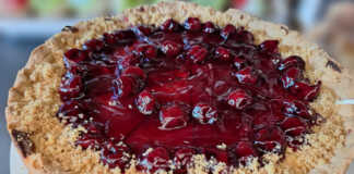 Πλούσιο κομμάτι ψητού cheesecake με παχιά στρώση κρέμας και κατακόκκινο γλυκό του κουταλιού βύσσινο να τρέχει στις πλευρές