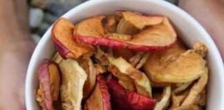 Φέτες αποξηραμένων μήλων τοποθετημένες σε ένα ξύλινο μπολ, έτοιμες για κατανάλωση ως υγιεινό σνακ.