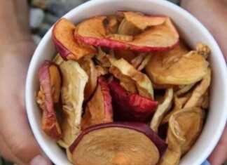 Φέτες αποξηραμένων μήλων τοποθετημένες σε ένα ξύλινο μπολ, έτοιμες για κατανάλωση ως υγιεινό σνακ.