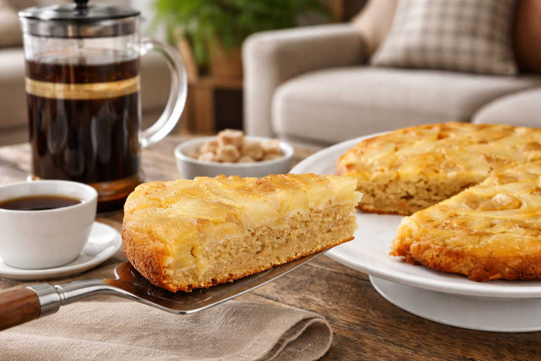 Μια αφράτη πίτα με αχλάδι πασπαλισμένη με άχνη ζάχαρη και ολόκληρα καρύδια στην επιφάνεια