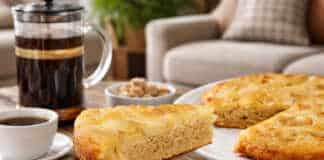 Μια αφράτη πίτα με αχλάδι πασπαλισμένη με άχνη ζάχαρη και ολόκληρα καρύδια στην επιφάνεια