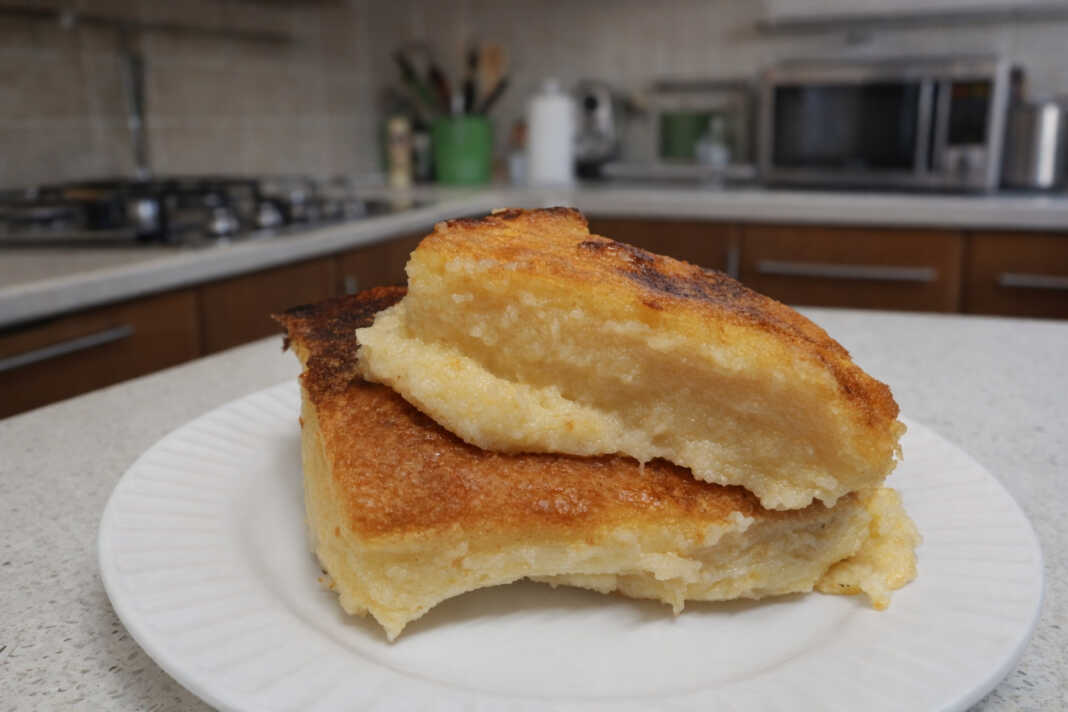 Μια χρυσαφένια παραδοσιακή γαλατόπιτα πασπαλισμένη με άχνη ζάχαρη και κανέλα μέσα στο ταψί της