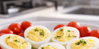 Πιατέλα με συμμετρικά γεμιστά αυγά, με κρεμώδη κίτρινη γέμιση και γαρνιτούρα από φρέσκο άνηθο.