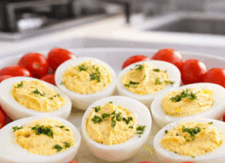 Πιατέλα με συμμετρικά γεμιστά αυγά, με κρεμώδη κίτρινη γέμιση και γαρνιτούρα από φρέσκο άνηθο.