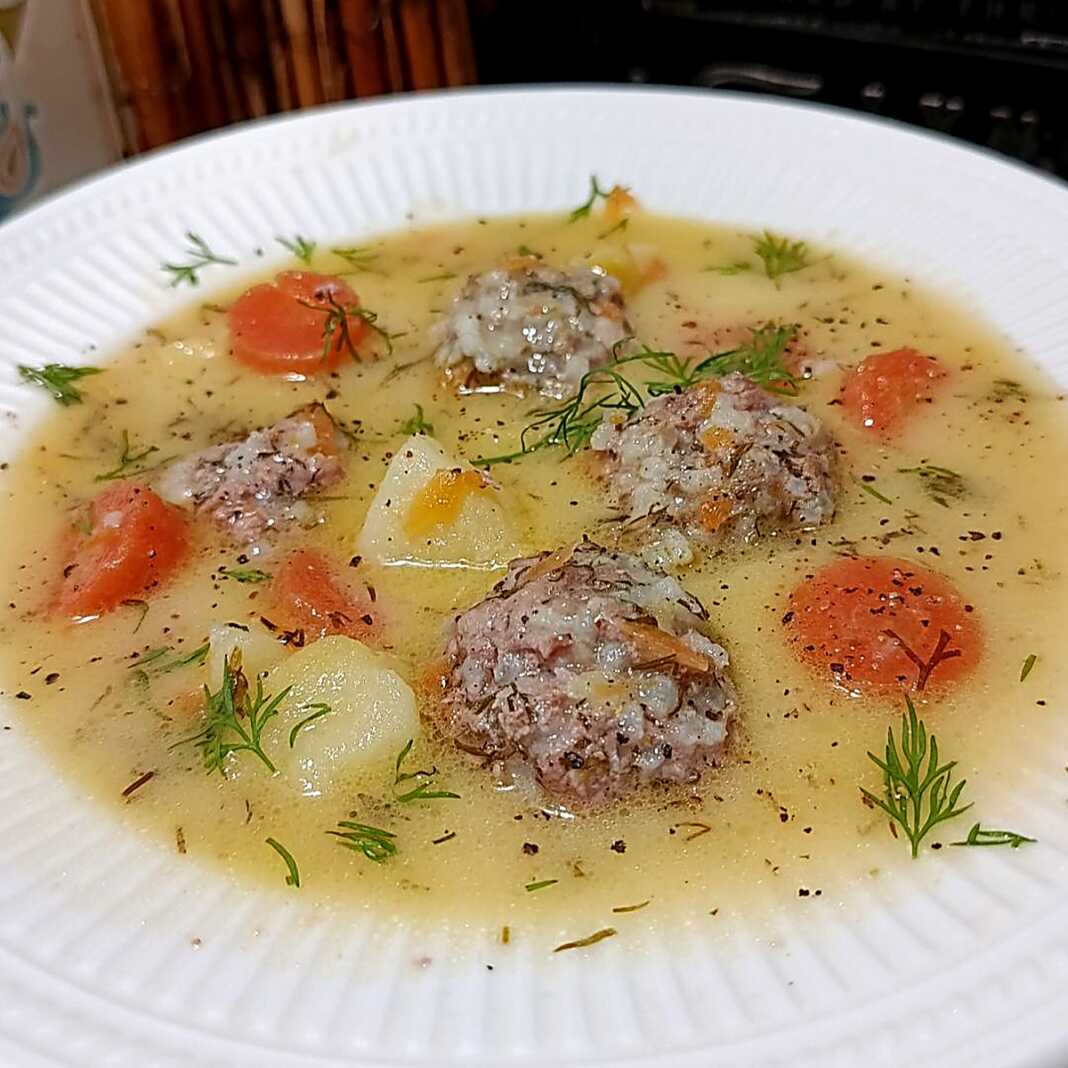 Μια βαθιά πιατέλα με ζεστά γιουβαρλάκια σε λευκή σάλτσα αυγολέμονο με κομματάκια καρότου και φρέσκο άνηθο