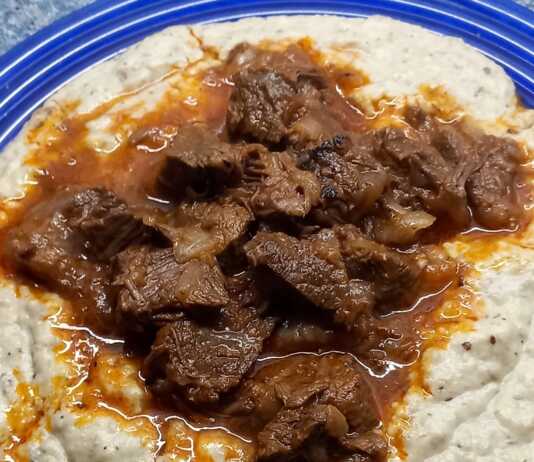 Ένα πλούσιο πιάτο Χουνκιάρ Μπεγιεντί με τρυφερό κοκκινιστό μοσχάρι πάνω σε βελούδινο λευκό πουρέ μελιτζάνας, γαρνιρισμένο με φρέσκο μαϊντανό.