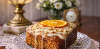 Ζουμερό κέικ καρότου-πορτοκαλιού με λευκό γλάσο τυριού και ξύσμα πορτοκαλιού σε ξύλινη επιφάνεια