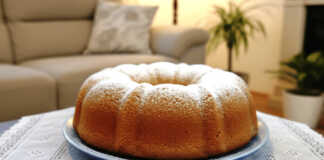 Ένα χρυσαφένιο αφράτο κέικ καρότου πασπαλισμένο με άχνη ζάχαρη πάνω σε μια μεταλλική σχάρα.