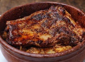 Σιγομαγειρεμένη χοιρινή κορτεζίνα μέσα σε πήλινο σκεύος, με πλούσια σκούρα σάλτσα και αρωματικά κρεμμύδια.