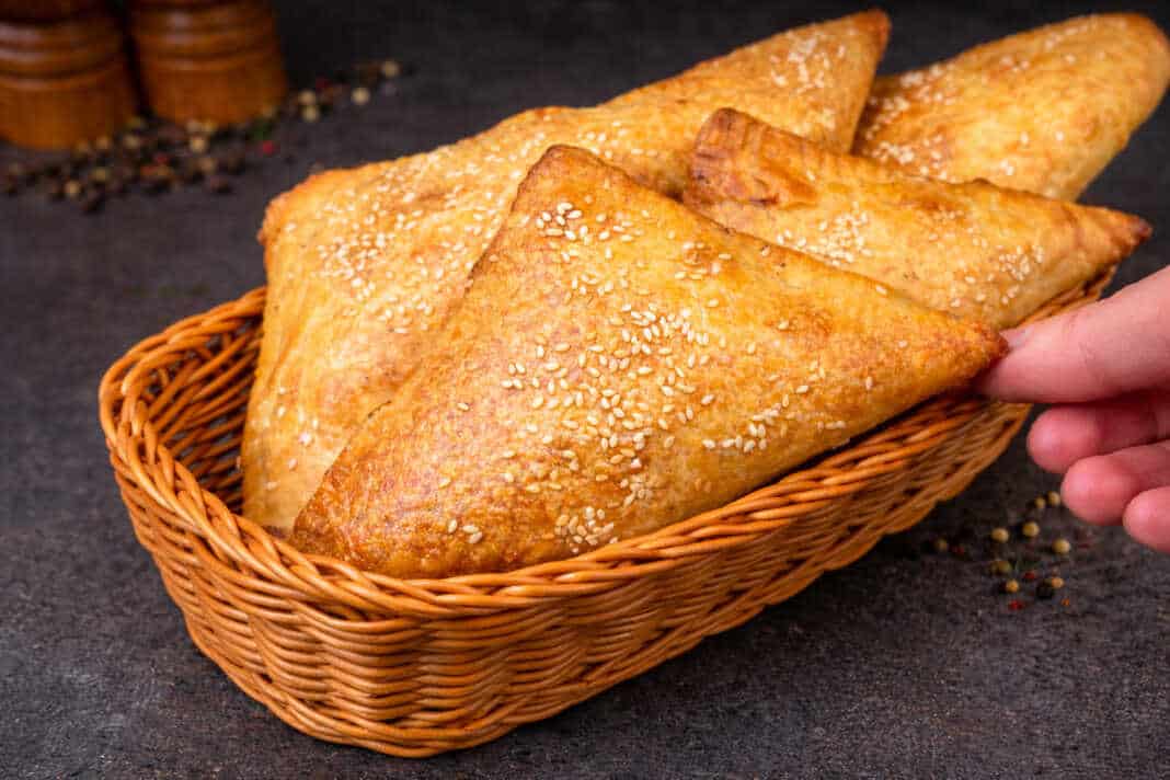 Τραγανά και χρυσαφένια κοτοπιτάκια σφολιάτας με σουσάμι σε σειρά πάνω σε ταψί