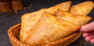 Τραγανά και χρυσαφένια κοτοπιτάκια σφολιάτας με σουσάμι σε σειρά πάνω σε ταψί