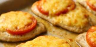 Ψητά φιλετάκια κοτόπουλου καλυμμένα με λιωμένο τυρί, φέτες ντομάτας και χρυσή κρούστα.