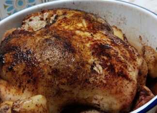 Ένα ολόκληρο ροδοκοκκινισμένο κοτόπουλο γεμιστό με ρύζι, περιτριγυρισμένο από μελωμένες πατάτες baby μέσα σε ένα κεραμικό πλακερό.