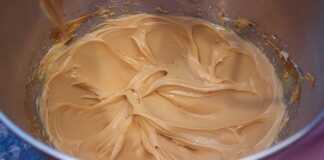 Μια μπολ με πλούσια, γυαλιστερή καραμελένια κρέμα με βελούδινη υφή και χρυσαφένιο χρώμα.