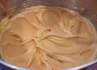 Μια μπολ με πλούσια, γυαλιστερή καραμελένια κρέμα με βελούδινη υφή και χρυσαφένιο χρώμα.