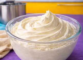 Ένα μπολ με λευκή, πλούσια και σταθερή κρέμα βουτύρου που έχει σχηματίσει κορυφές, έτοιμη για διακόσμηση.