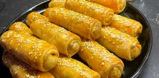 Μικρές ροδοκοκκινισμένες λαχανόπιτες Σαρακοστής αλειμμένες με αυγό και πασπαλισμένες με σουσάμι πάνω σε λαδόκολλα