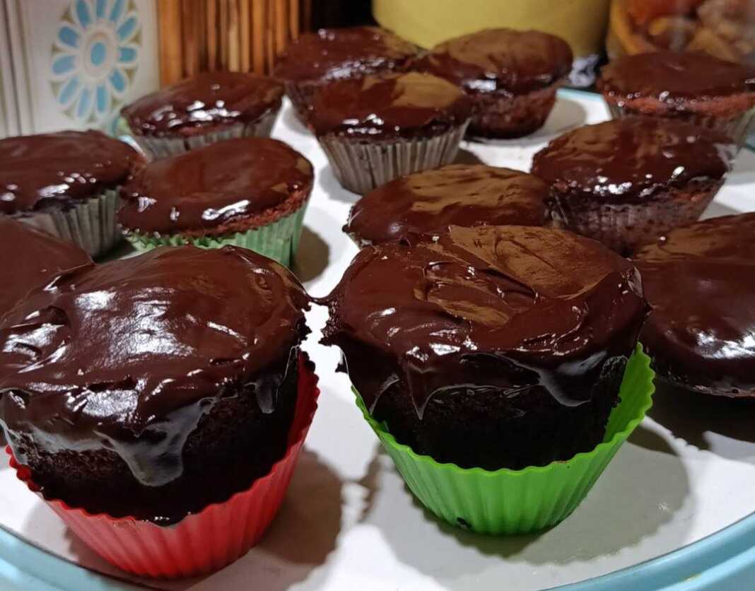 Αφράτα μάφιν πορτοκαλιού με επικάλυψη γυαλιστερού γλάσου σοκολάτας, τοποθετημένα σε μια βάση σερβιρίσματος.