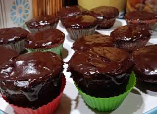 Αφράτα μάφιν πορτοκαλιού με επικάλυψη γυαλιστερού γλάσου σοκολάτας, τοποθετημένα σε μια βάση σερβιρίσματος.