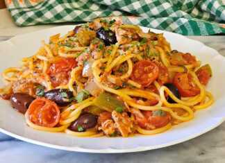 Μια αχνιστή μακαρονάδα με τόνο, κόκκινη σάλτσα, ελιές και φρέσκο βασιλικό σε λευκό πιάτο