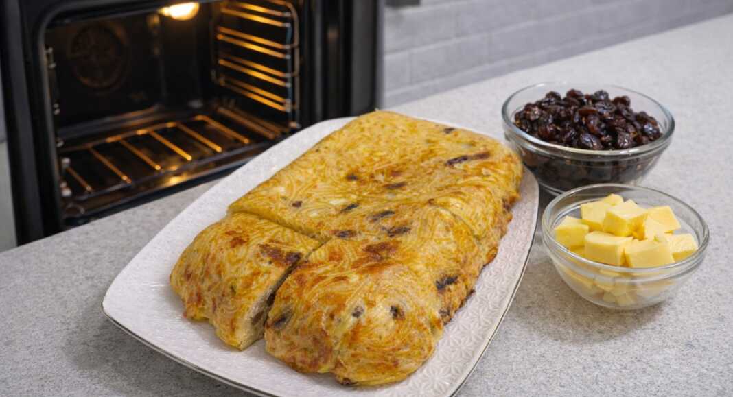 Χρυσαφένια μακαρονοπιτα φούρνου κομμένα σε κομμάτια πασπαλισμένα με ζάχαρη και γεμάτα σταφίδες