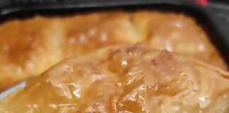 Ένα κομμάτι ροδοκοκκινισμένο σιροπιαστό γλυκό που συνδυάζει στρώσεις μπακλαβά με καρύδια και πλούσια κρέμα γαλακτομπούρεκου.