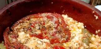 Ένα πήλινο σκεύος με λιωμένη φέτα, ντομάτα και καυτερή πιπεριά, πασπαλισμένο με μπόλικη ρίγανη.