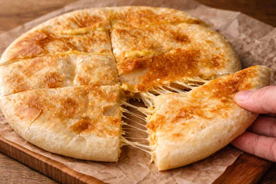 Χρυσαφένιο πατατόψωμο στο τηγάνι που κόβεται στη μέση και τρέχει λιωμένη μοτσαρέλα