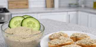 Ένα μπολ με βελούδινο πατέ μελιτζάνας γαρνιρισμένο με ολόκληρα καρύδια και φρέσκα μυρωδικά.