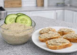 Ένα μπολ με βελούδινο πατέ μελιτζάνας γαρνιρισμένο με ολόκληρα καρύδια και φρέσκα μυρωδικά.