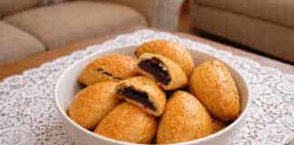 Σειρά από χρυσαφένια πιτάκια με δαμάσκηνα, αλειμμένα με γυαλιστερή μαρμελάδα, τοποθετημένα σε μια ξύλινη επιφάνεια.