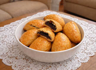 Σειρά από χρυσαφένια πιτάκια με δαμάσκηνα, αλειμμένα με γυαλιστερή μαρμελάδα, τοποθετημένα σε μια ξύλινη επιφάνεια.