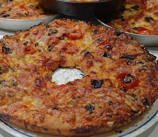 Ένα ταψί με λαχταριστή σπιτική πίτσα με πλούσιο τυρί και σάλτσα ντομάτας, με τη ζύμη να φαίνεται εξαιρετικά αφράτη στις άκρες.