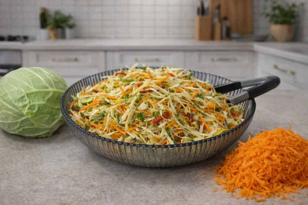 Μια πολύχρωμη και φρέσκια σαλάτα με ψιλοκομμένο λάχανο, καρότο, πιπεριές και αγγούρι, περιχυμένη με πράσινη σάλτσα μυρωδικών