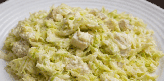 Μια μεγάλη σαλατιέρα με ψιλοκομμένο λάχανο, κομμάτια στήθος κοτόπουλο και κρεμώδη σως γιαουρτιού.