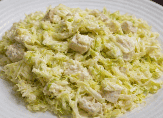 Μια μεγάλη σαλατιέρα με ψιλοκομμένο λάχανο, κομμάτια στήθος κοτόπουλο και κρεμώδη σως γιαουρτιού.