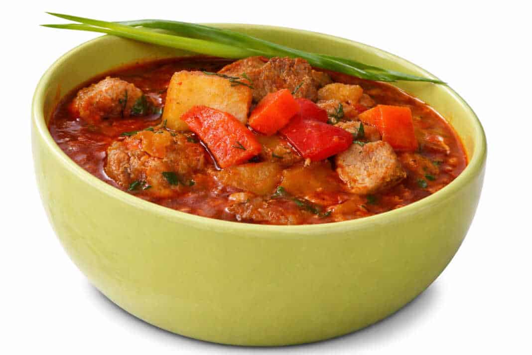 Αχνιστή σούπα γκούλας σε πήλινο μπολ με μεγάλα κομμάτια κρέατος πατάτες και κατακόκκινη σάλτσα παπρίκας