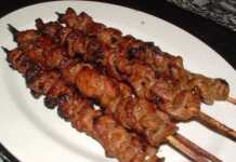 Ζουμερά χοιρινά σουβλάκια με κρεμμύδι και μπέικον τοποθετημένα όρθια μέσα σε γυάλινα βάζα στον φούρνο.