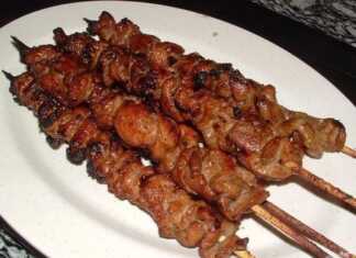 Ζουμερά χοιρινά σουβλάκια με κρεμμύδι και μπέικον τοποθετημένα όρθια μέσα σε γυάλινα βάζα στον φούρνο.