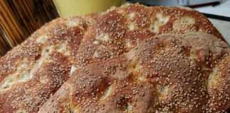 Δύο μεγάλες παραδοσιακές λαγάνες με δαχτυλιές και άφθονο σουσάμι πάνω σε λαδόκολλα μόλις βγήκαν από τον φούρνο