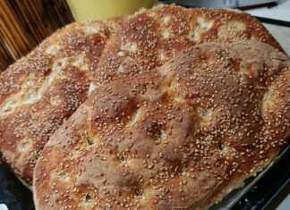 Δύο μεγάλες παραδοσιακές λαγάνες με δαχτυλιές και άφθονο σουσάμι πάνω σε λαδόκολλα μόλις βγήκαν από τον φούρνο