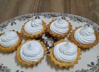 Σειρά από χρυσαφένια ταρτάκια γεμισμένα με κόκκινη μαρμελάδα και ψηλές κορυφές λευκής μαρέγκας.