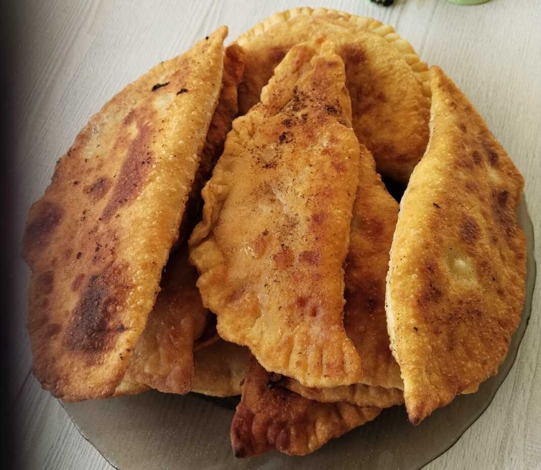 Χρυσαφένια τηγανιτά πιτάκια μέσα σε ένα πιάτο, με λιωμένο τυρί και κομμάτια μπέικον να φαίνονται στο εσωτερικό τους.