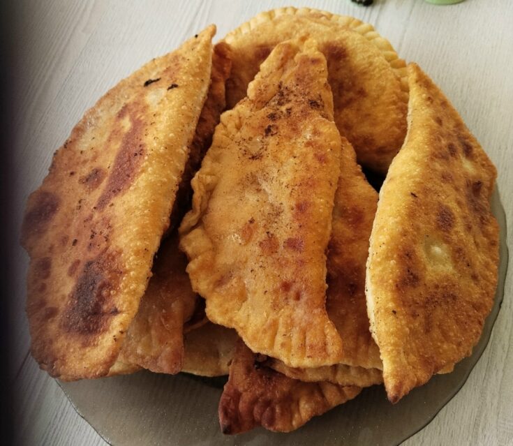 Χρυσαφένια τηγανιτά πιτάκια μέσα σε ένα πιάτο, με λιωμένο τυρί και κομμάτια μπέικον να φαίνονται στο εσωτερικό τους.