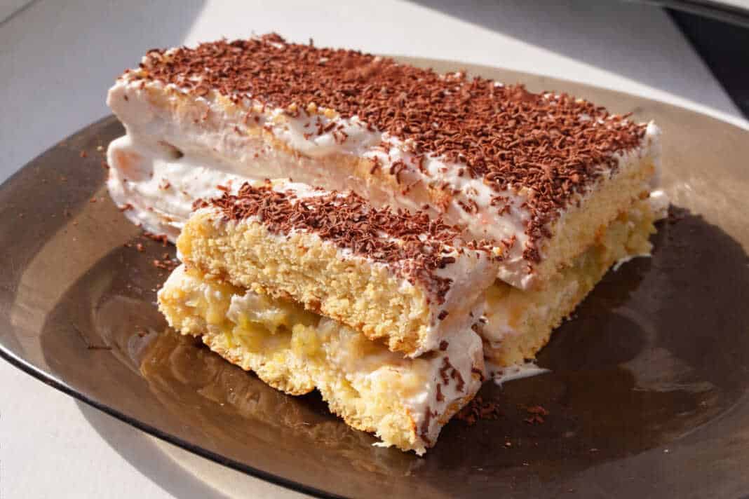 Μια κομψή τούρτα με στρώσεις παντεσπανιού, γεμισμένη με καραμελωμένα μήλα και λευκή κρέμα τυριού.