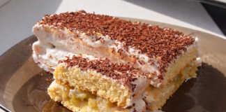 Μια κομψή τούρτα με στρώσεις παντεσπανιού, γεμισμένη με καραμελωμένα μήλα και λευκή κρέμα τυριού.