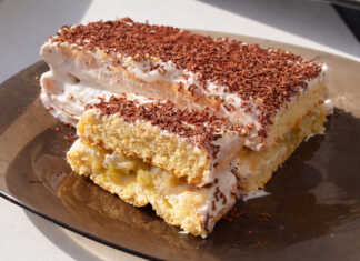 Μια κομψή τούρτα με στρώσεις παντεσπανιού, γεμισμένη με καραμελωμένα μήλα και λευκή κρέμα τυριού.