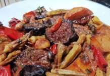 Ένα ταψί με παραδοσιακό τουρλού λαχανικών, με μελιτζάνες, πιπεριές και μπάμιες σε πλούσια κόκκινη σάλτσα, γαρνιρισμένο με φρέσκο μαϊντανό.