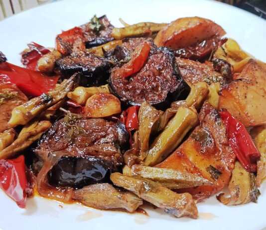 Ένα ταψί με παραδοσιακό τουρλού λαχανικών, με μελιτζάνες, πιπεριές και μπάμιες σε πλούσια κόκκινη σάλτσα, γαρνιρισμένο με φρέσκο μαϊντανό.