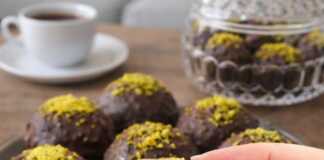 Στρογγυλά σοκολατένια τρουφάκια καλυμμένα με γυαλιστερό γλάσο σοκολάτας, τοποθετημένα επάνω σε λαδόκολλα.